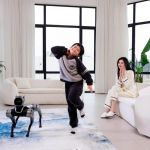 Magicdog Pro Roboterhund beobachtet tanzenden Jungen, Frau applaudiert im Wohnzimmer